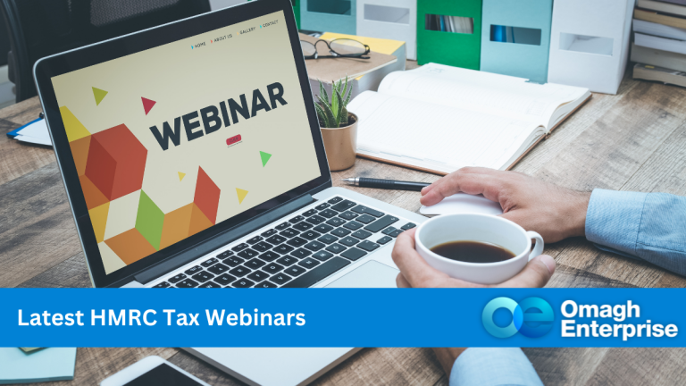 A hand, holding a cup of coffee, in front of an opened laptop on a desk full of paperwork. On the laptop monitor there is a PowerPoint presentation with the word WEBINAR on it. A blue banner along the bottom, with "Latest HMRC Tax Webinars" written in white writing. Omagh Enterprise logo within the blue banner.