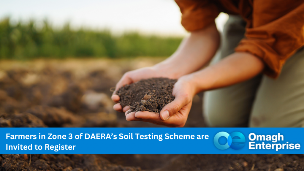 A close up of a person kneeling in a field. They are cupping some soil in their hands. Blue banner along the bottom. White text "Farmers in Zone 3 of DAERA’s Soil Testing Scheme are Invited to Register" Omagh Enterprise logo is within the banner.
