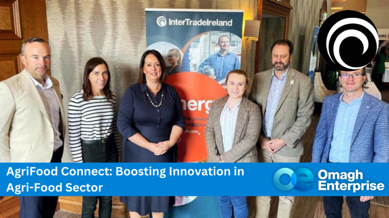 Six people standing indoors at an event, with a banner promoting InterTradeIreland. Text on the image reads: AgriFood Connect: Boosting Innovation in Agri-Food Sector, accompanied by the Omagh Enterprise logo.